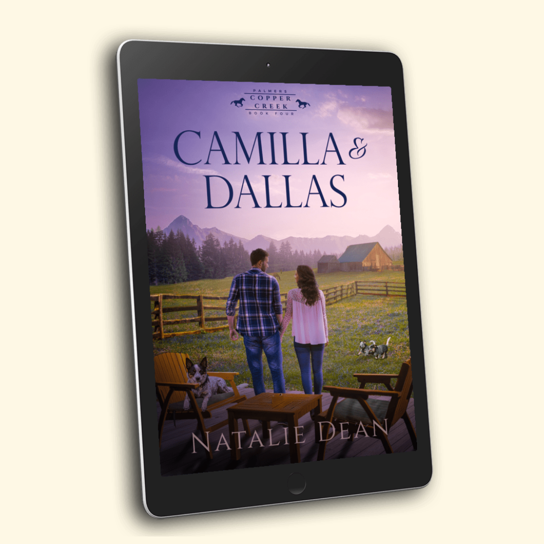 Ebook cover for – Camilla & Dallas, Palmers of Copper Creek Book Four by Natalie Dean, a wholesome small-town cowboy romance: a couple stands hand in hand facing a sunlit pasture; Adirondack chairs and table on a wooden deck; a herding dog lounges on a chair while two playful puppies romp in the grass; split-rail fences, a rustic barn, pine forest, and purple mountain peaks under a pink-gold evening sky.